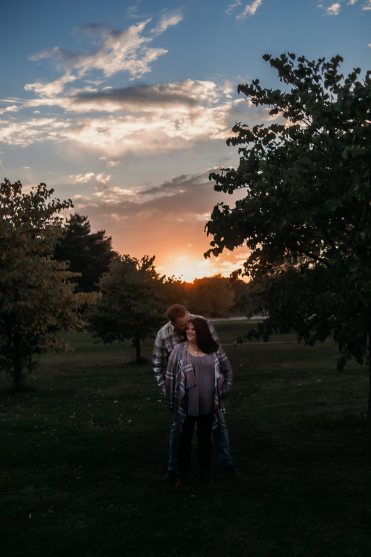 woman, standing in front of man, man snuggled in close, with beautiful sunset behind them, in foster park, fort wayne, indiana